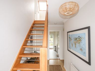 A hallway with wooden stairs leading up and a framed map on the wall at The Palms in Abersoch