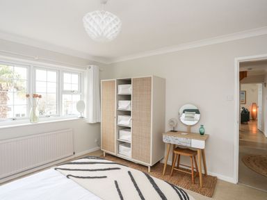 A bedroom with a bed a wardrobe a dressing table stool and a window at The Palms in Abersoch