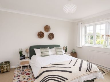 A bedroom with a bed, two nightstands with lamps, three decorative wall baskets and a window at The Palms in Abersoch