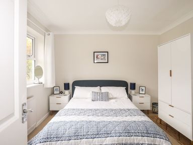 A bedroom with a bed between two nightstands and a wardrobe at The Palms in Abersoch