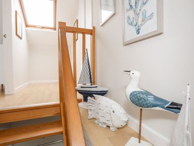 A stairway landing with wooden railings and nautical decorations including a fish, a bird, and a sailboat model at The Palms in Abersoch