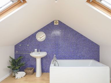 A bathroom with a white pedestal sink and bathtub against a blue tiled wall at The Palms in Abersoch