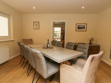 A dining room with a large table surrounded by chairs and wine glasses on the table at Whimhowe in Windermere