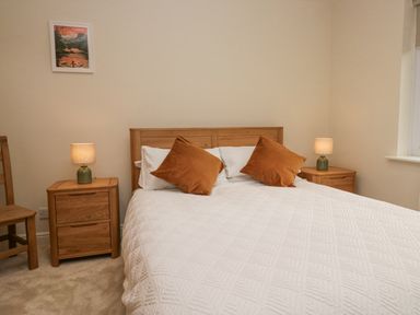 A bedroom with a wooden bed and nightstands with lamps at Whimhowe in Windermere