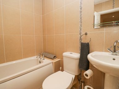 A bathroom with a bathtub toilet sink and towels at Whimhowe in Windermere