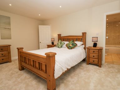 A bedroom with a wooden bed and bedside tables with lamps at Whimhowe in Windermere
