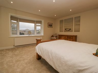 A bedroom with a wooden bed and dresser a window with blinds and a heart artwork on the wall at Whimhowe in Windermere
