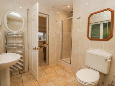 A bathroom with a toilet sink shower and two mirrors at Whimhowe in Windermere