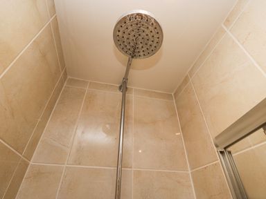 A close up of a showerhead and tiled walls in a shower area at Whimhowe in Windermere