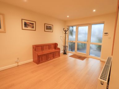 An entryway with wooden bench coat rack framed pictures and frosted glass door at Whimhowe in Windermere