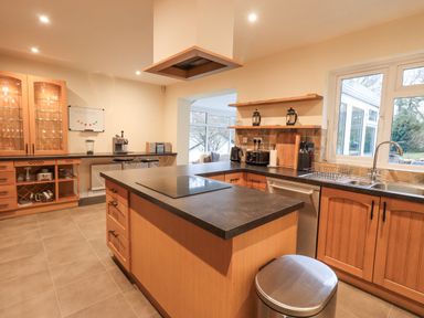 A kitchen with a wooden island countertop a sink a window cabinets and kitchen appliances at Whimhowe in Windermere