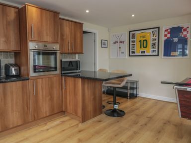 A kitchen with wood cabinets and bar stools at Whimhowe in Windermere