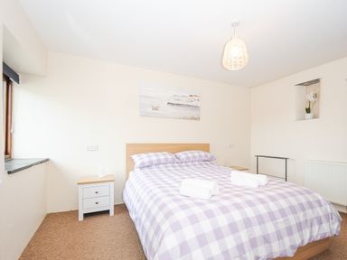A bedroom with a bed with checkered bedding and two towels on top at The Dairy Barn in Camelford