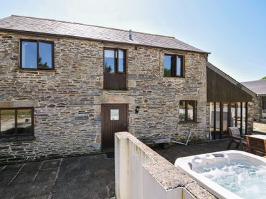 An outdoor view of a stone building with a spa at The Dairy Barn Camelford