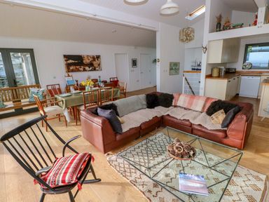 A living room with a sectional sofa and dining area at Green Shutters Freshwater East near Lamphey