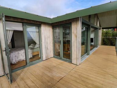 An outdoor deck area with glass doors leading to a bedroom at Green Shutters Freshwater East near Lamphey
