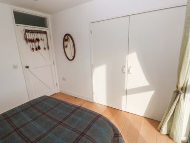 A bedroom featuring a bed and a wardrobe at Green Shutters Freshwater East near Lamphey