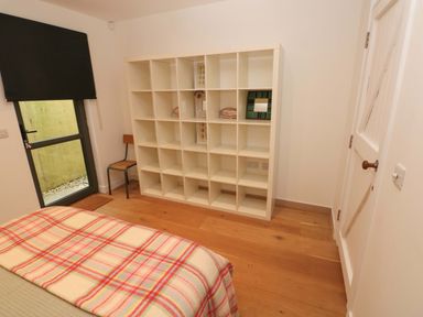 A bedroom with a bed and a shelving unit at Green Shutters in Freshwater East near Lamphey
