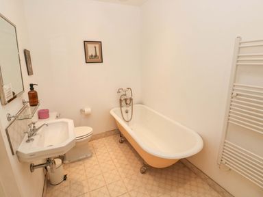 A bathroom with a bathtub, sink, toilet, and towel radiator at Green Shutters, Freshwater East near Lamphey