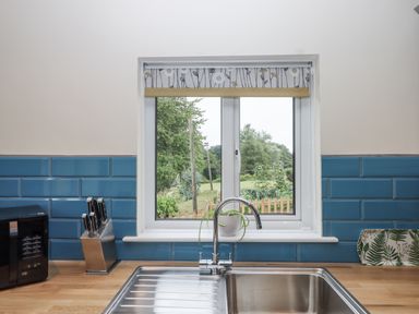 A kitchen with a sink and window overlooking the garden at Aunty Junes Cottage Okehampton