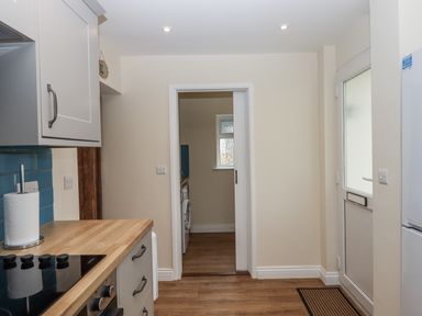 A kitchen with cabinets and a doorway leading to another room at Aunty Junes Cottage in Okehampton