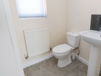 A bathroom with a toilet sink radiator and a window at 9 Beckett Close in Colwyn Bay
