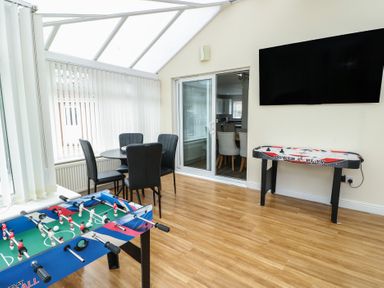 A conservatory with a foosball table and air hockey table at 9 Beckett Close in Colwyn Bay