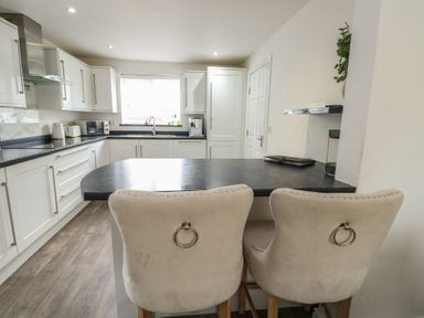 A kitchen with bar stools and a window at 9 Beckett Close in Colwyn Bay