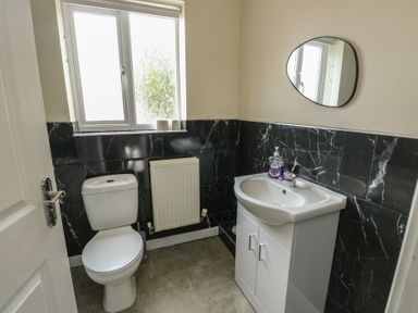 A bathroom with a toilet, sink, and window at 9 Beckett Close Colwyn Bay