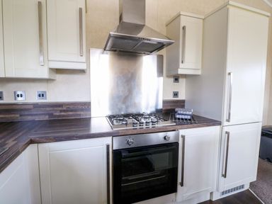 A kitchen with gas stove oven white cabinets and dark countertop at Crathie Lodge Banavie near Caol
