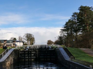 A canal lock with trees and buildings on either side at Crathie Lodge in Banavie near Caol