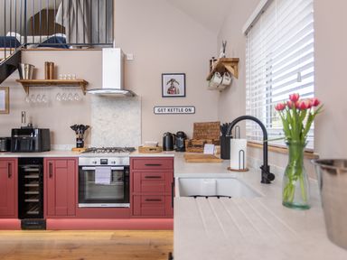 A kitchen with red cabinets a sink with a black faucet and tulips in a vase at Hares Hill in Thornton-Le-Dale