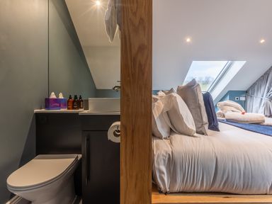 A bathroom with a toilet and sink next to a bedroom with a bed and pillows at Hares Hill in Thornton-Le-Dale
