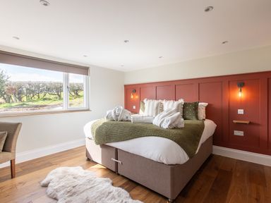 A bedroom with a large bed with pillows and robes near a window at Hares Hill in Thornton-Le-Dale