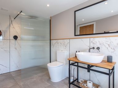 A bathroom with a toilet a washbasin on a wooden countertop and a shower area with a glass partition at Hares Hill in Thornton-Le-Dale