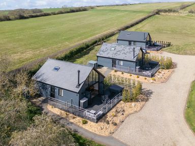 Three modern detached houses with fenced patios on gravel drive surrounded by fields at Hares Hill in Thornton-Le-Dale