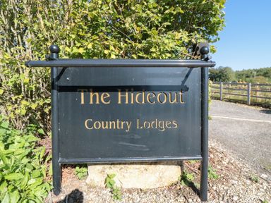 A sign for The Hideout Country Lodges with bushes and gravel at The Hideout in Thornton-Le-Dale