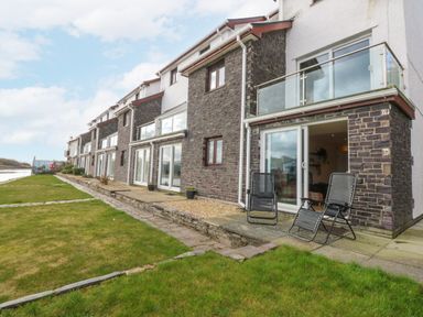 An outdoor view of a building with a terrace and chairs at Oakley View Apartment in Porthmadog