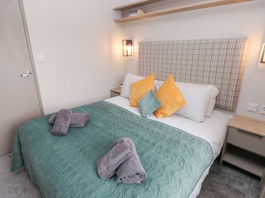 A bedroom with a bed with orange and green pillows and a green bedspread at Caldey Retreat Hasguard Cross near Broad Haven