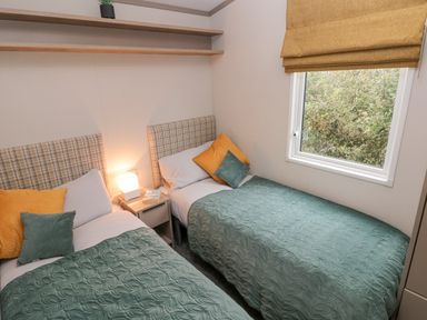 A bedroom with two single beds green bedspreads and a window at Caldey Retreat in Hasguard Cross near Broad Haven