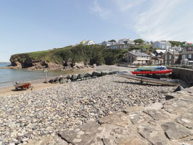 A beach with boats and houses in the background at Caldey Retreat Hasguard Cross near Broad Haven