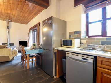 A kitchen and dining area with a refrigerator microwave dishwasher dining table and chairs at Owl Cottage in Ashen Cross Pelynt