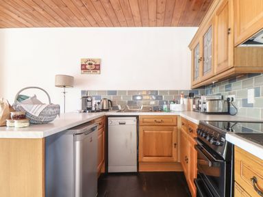 A kitchen with wooden cabinets stainless steel appliances and various kitchen items at Court Cottage Ashen Cross Pelynt
