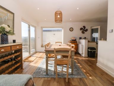 A dining room with a wooden table and chairs a wine rack and a wooden barrel at Awel-Y-Mor in Trearddur Bay