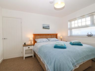 A bedroom with a double bed and bedside tables with lamps at Awel-Y-Mor in Trearddur Bay