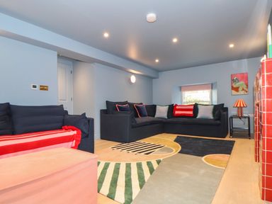 A living room with dark sofas a colorful rug and a red tiled fireplace at Mavericks Wave in St Agnes