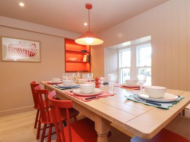 Dining room with red chairs wooden table set with bowls plates and glasses at Mavericks Wave in St Agnes