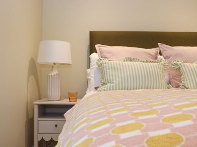A bedroom with a bed with pillows and a nightstand with a lamp and glass at Mavericks Wave in St Agnes
