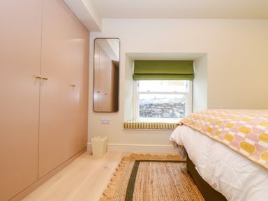 A bedroom with built in wardrobes mirror window seat and bed with patterned blanket at Mavericks Wave in St Agnes