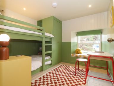 A bedroom with green bunk beds a window seat desk and stool at Mavericks Wave in St Agnes